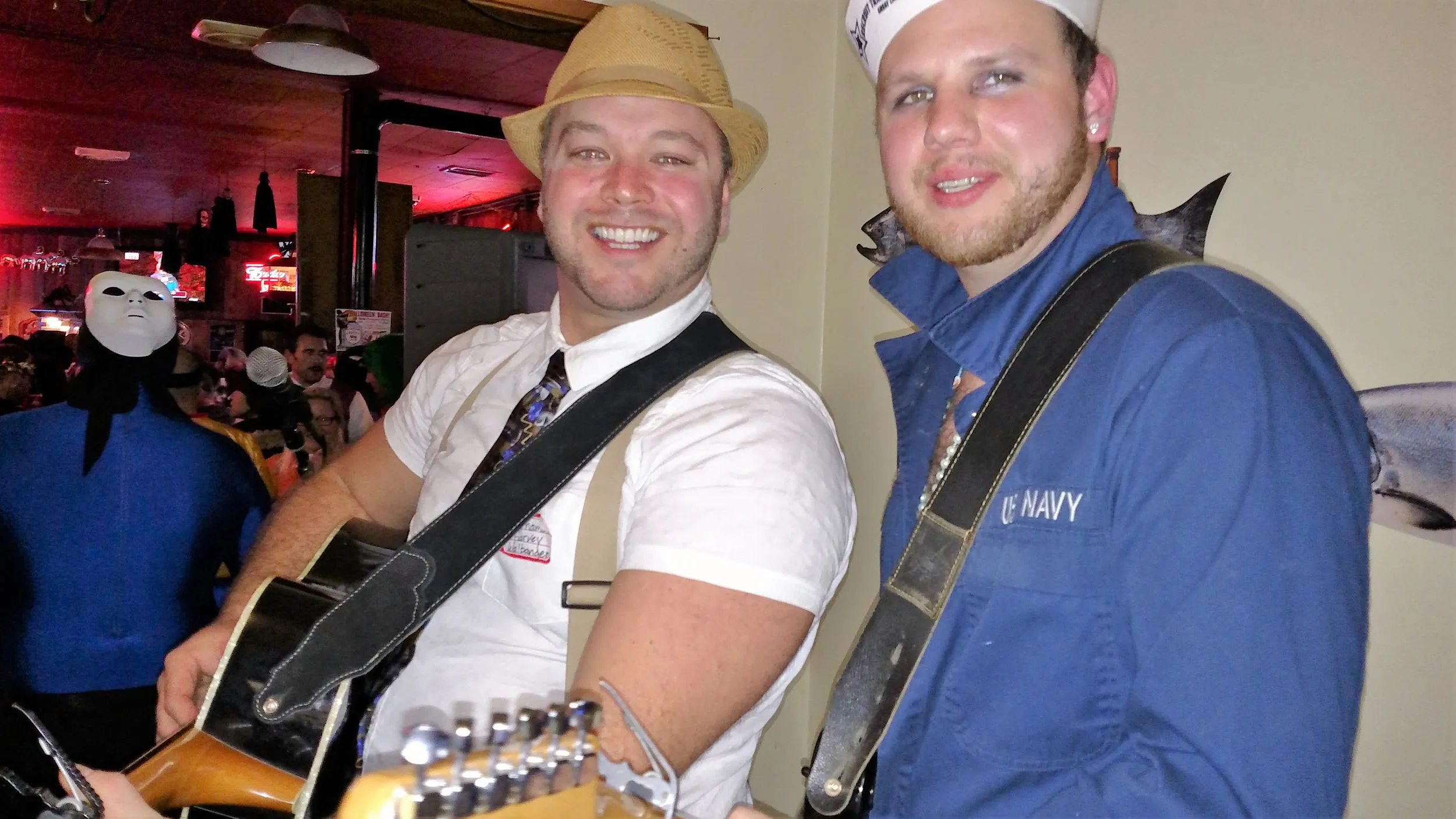 Two musicians with guitars and hats setting up at the stage, ready to play for the crowd.